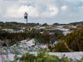 Lighthouse standing tall and strong over vast sand dunes